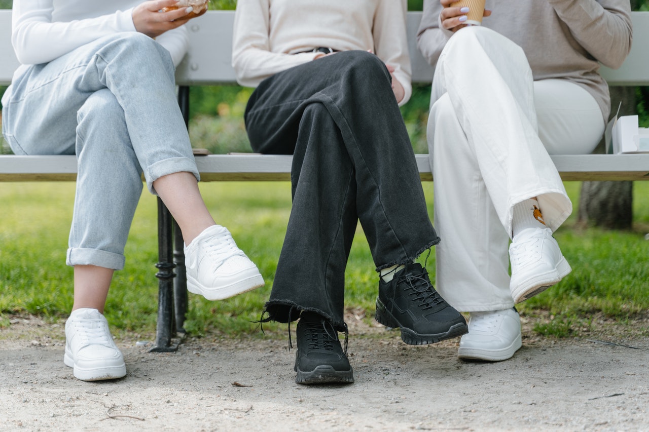 Three people sitting on bench with crossed legs