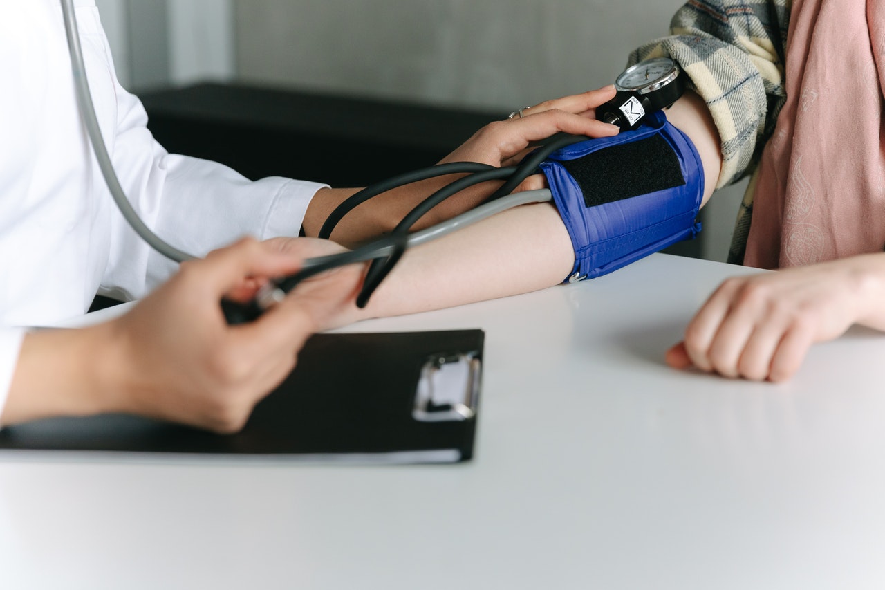 A person is at the doctor who is checking his blood pressure