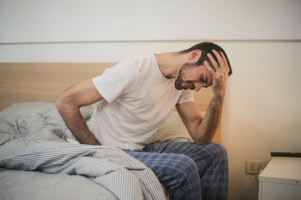 Man is sitting on bed with back pain