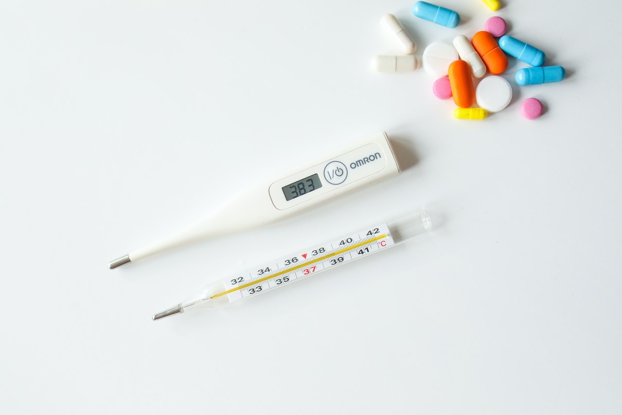 Two thermometer's on the table and few pills next to them