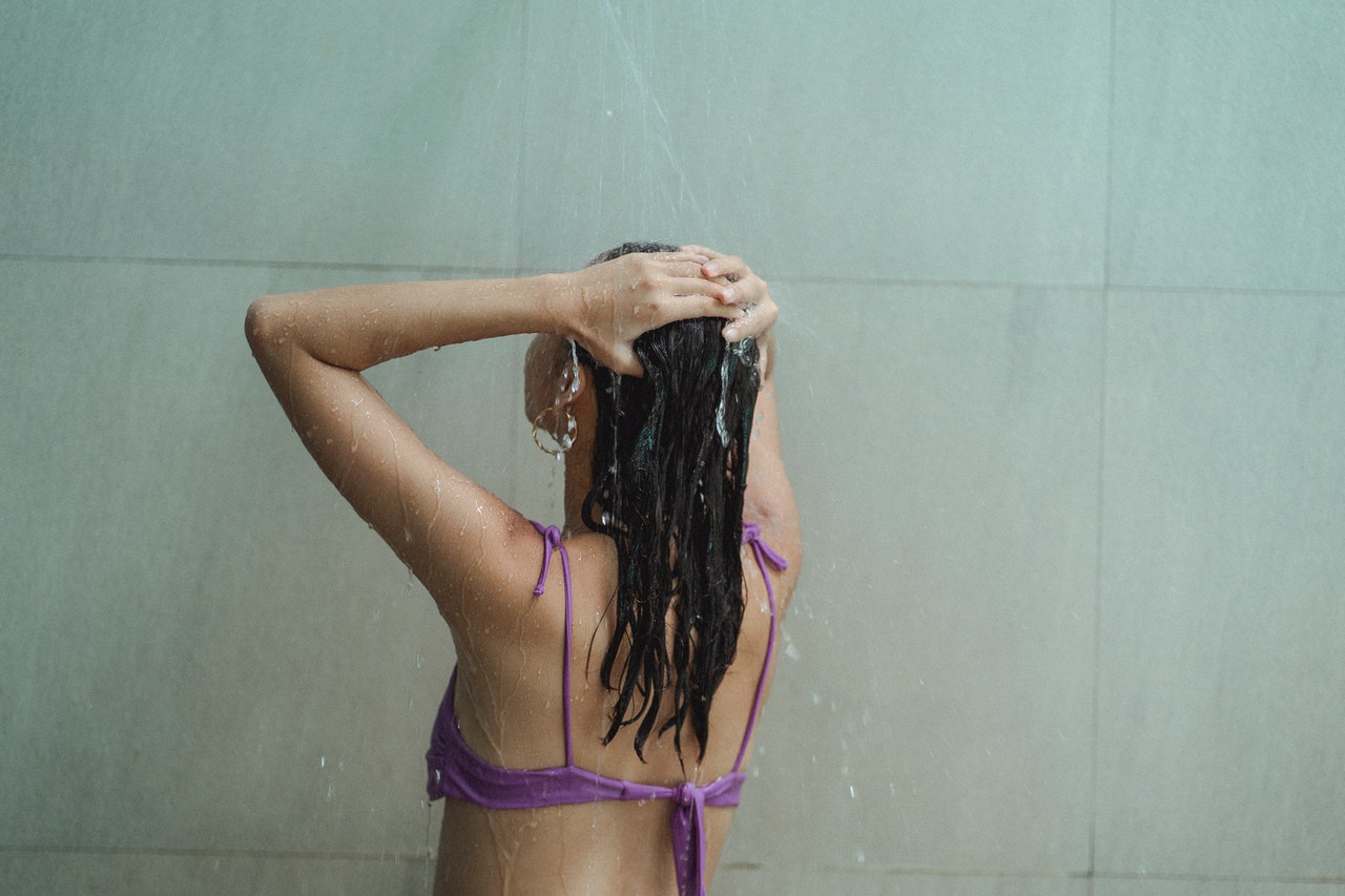 Woman is washing her hair under the shower